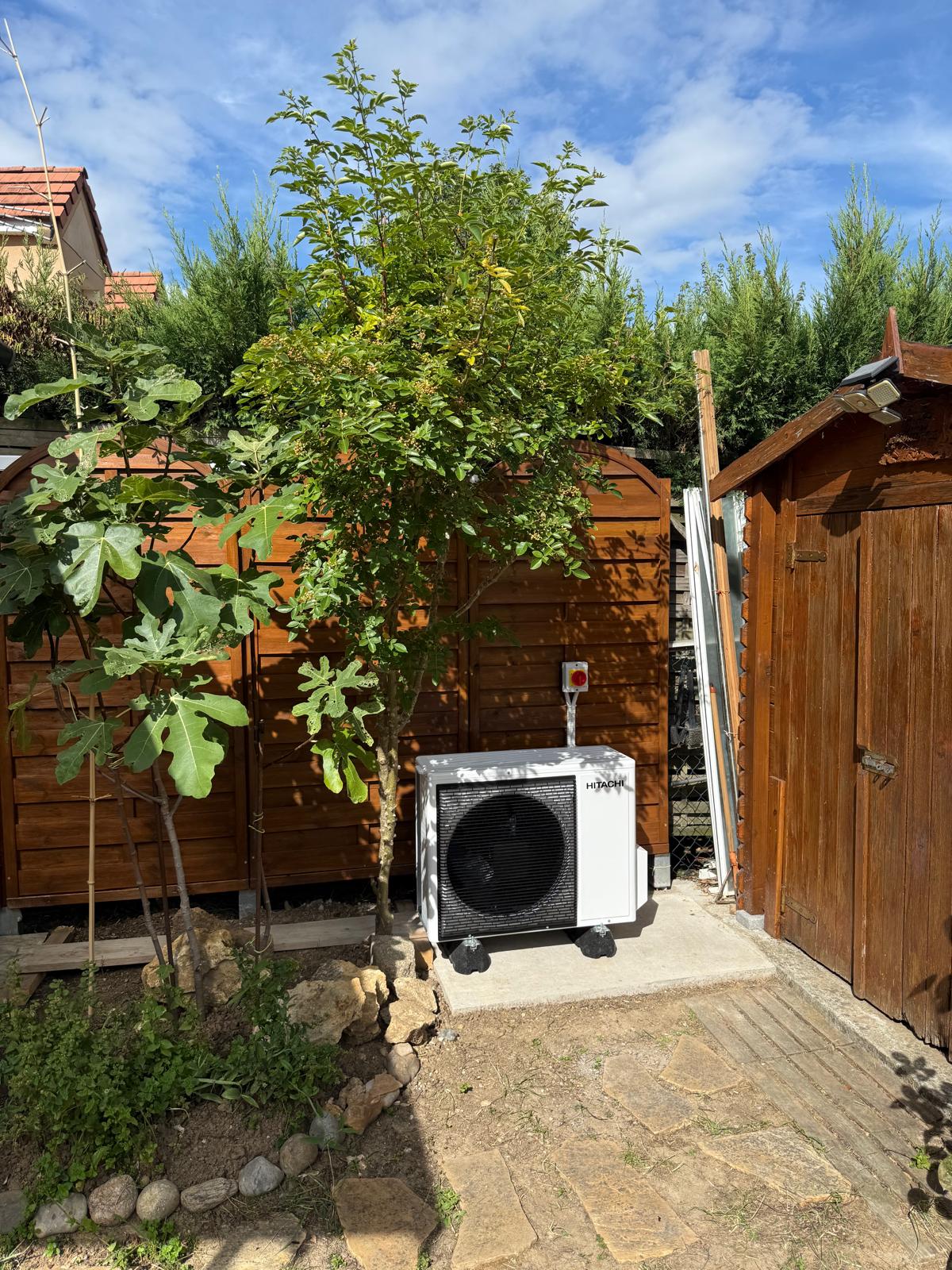 Unité extérieure de pompe à chaleur Hitachi installée dans un jardin par ASD Energie